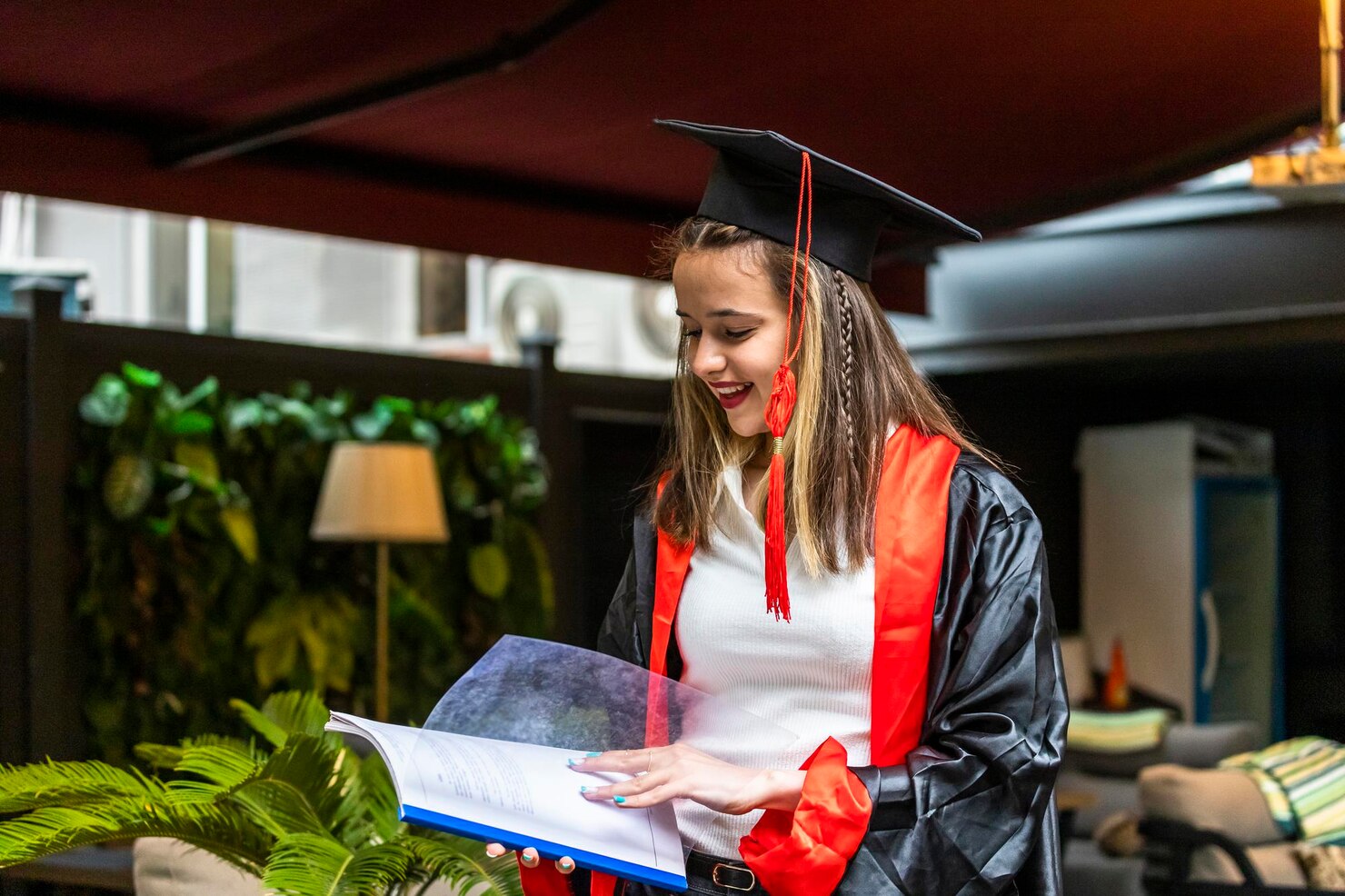 young-student-wearing-graduation-cape-looking-her-notebook_114579-92485